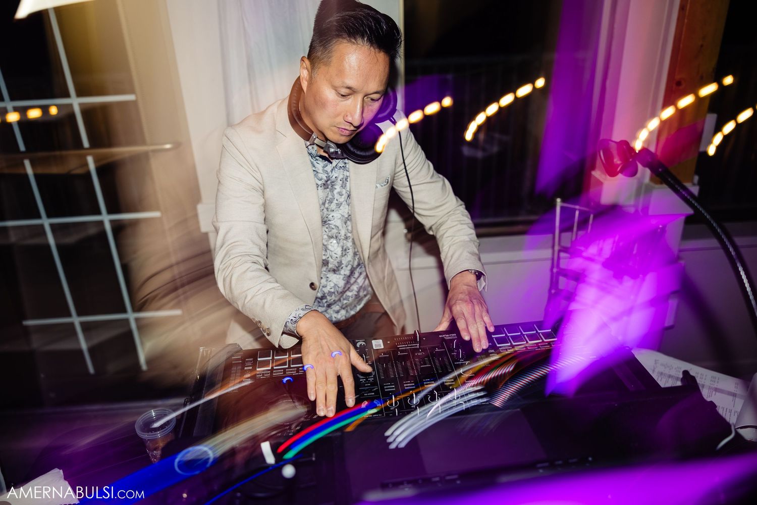 DJ performs at a wedding reception with purple lighting effects and professional sound equipment.