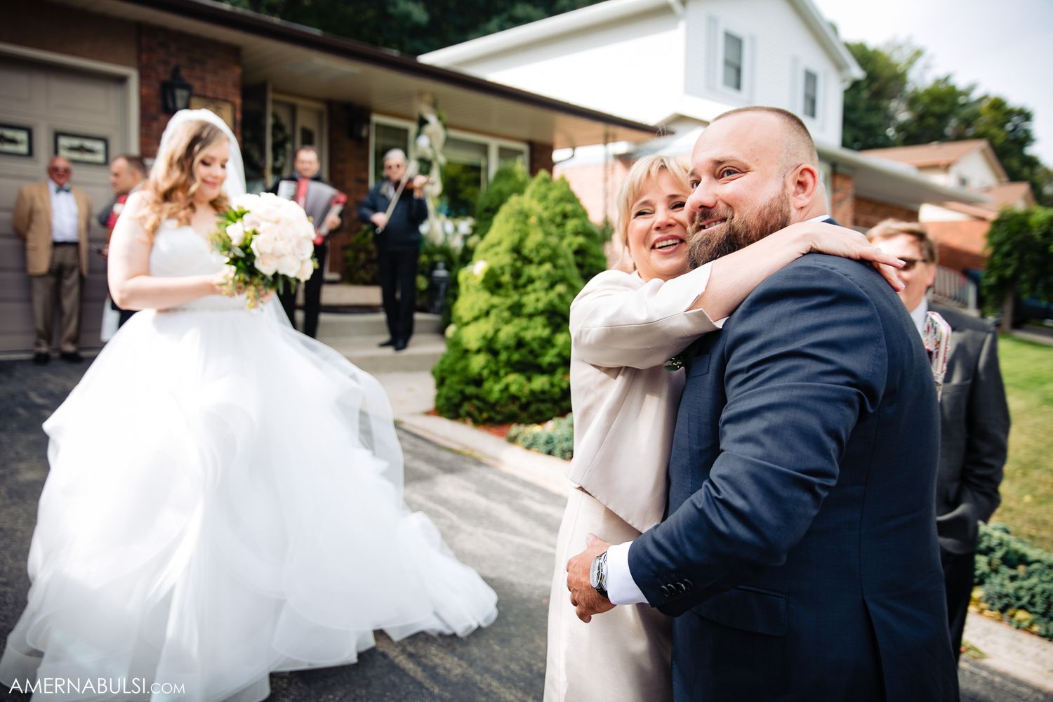 Wedding couple sharing a playful moment outside a residential building on their special day.