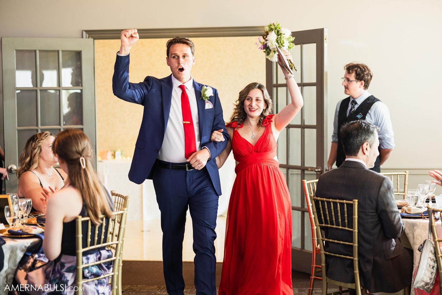 Wedding party members make grand entrance through doorway during reception celebration.