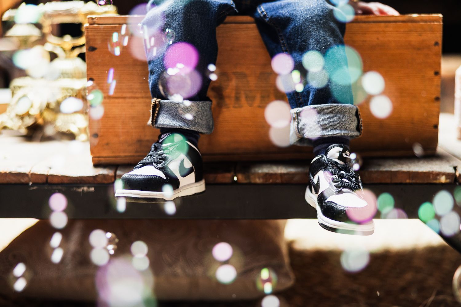 Black sneakers with colorful bokeh lights creating a dreamy effect on wooden steps.