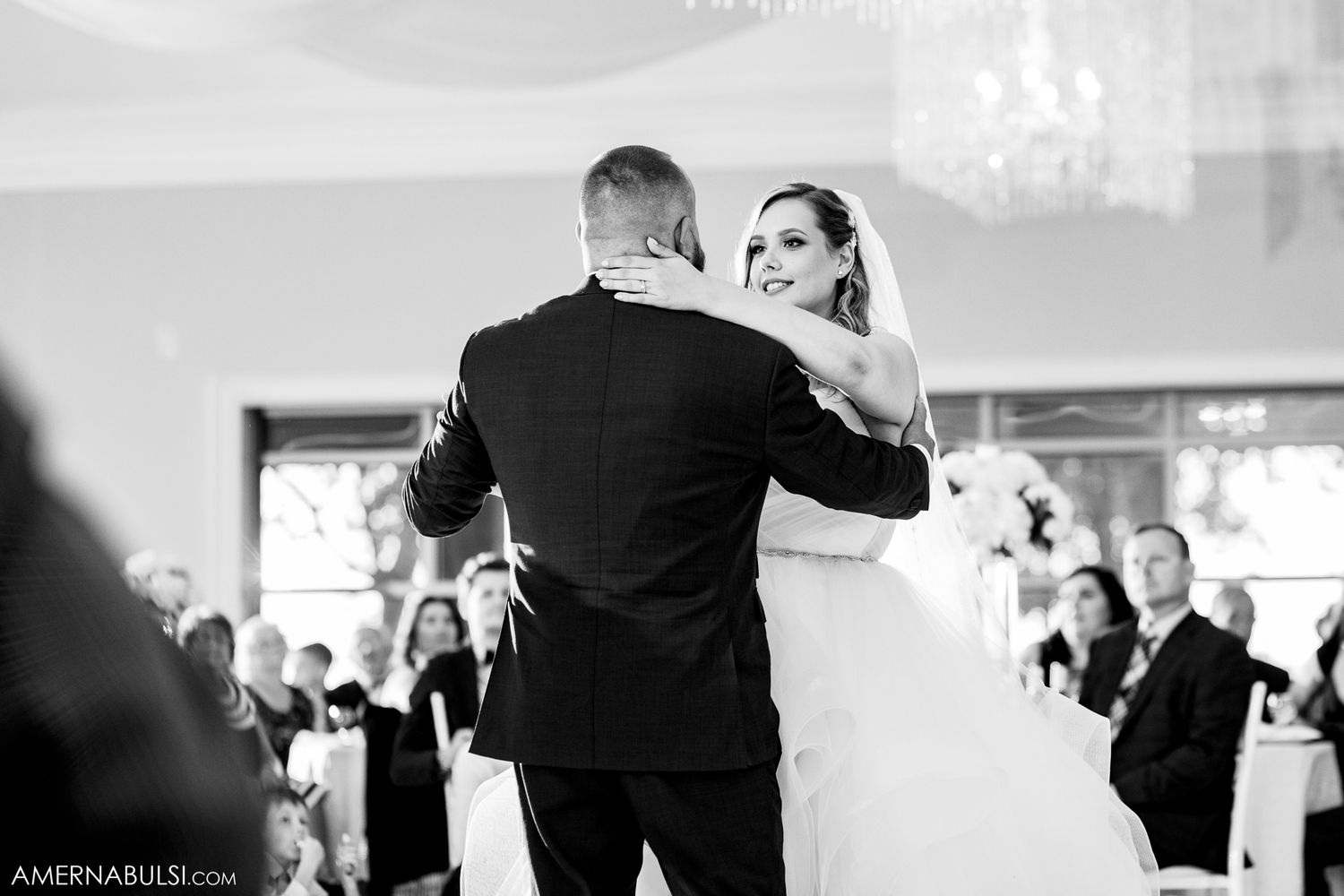Wedding reception guests dancing in an elegant ballroom captured in black and white.