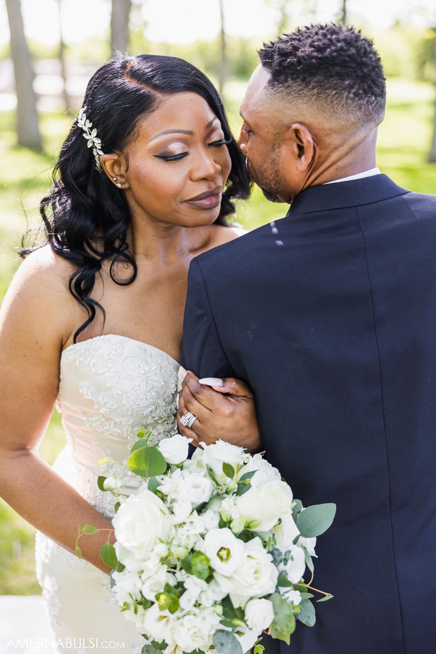 Romantic wedding portrait of couple sharing an intimate moment with white bouquet.