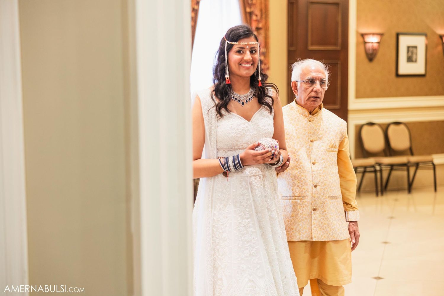White and gold decorated hallway scene during formal wedding celebration.