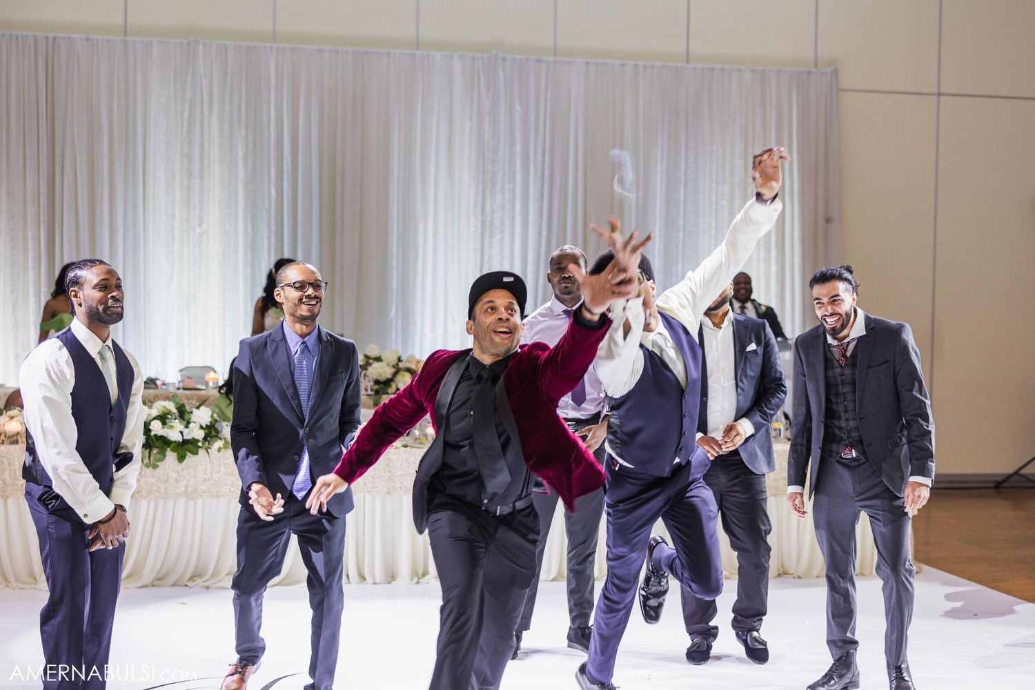 Group of groomsmen celebrating with energetic dance moves at wedding reception.