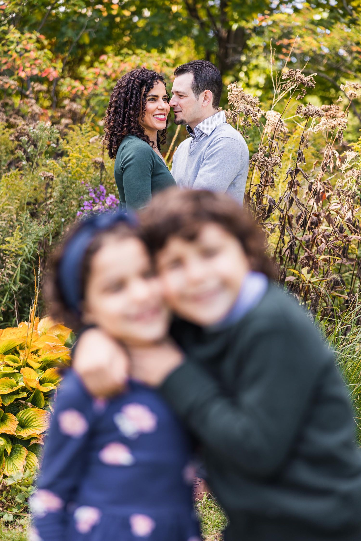 A romantic couple embraces in a garden surrounded by vibrant yellow fall foliage.