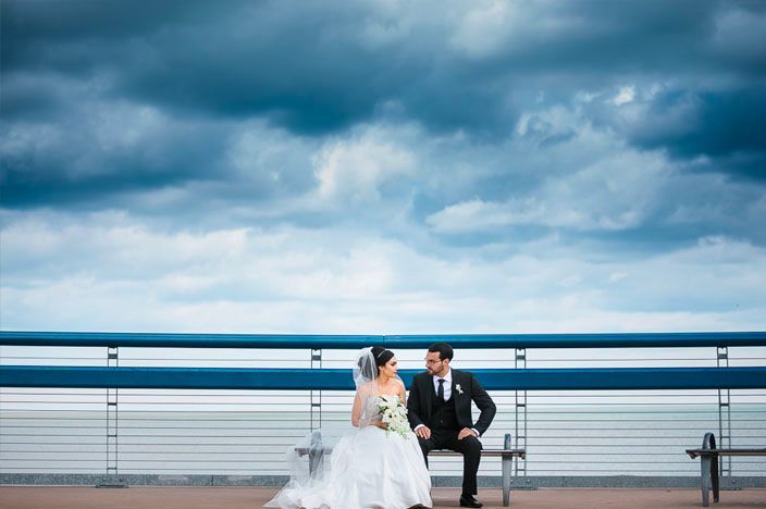 Dramatic cloudy sky over a beach boardwalk creates moody wedding photography backdrop.
