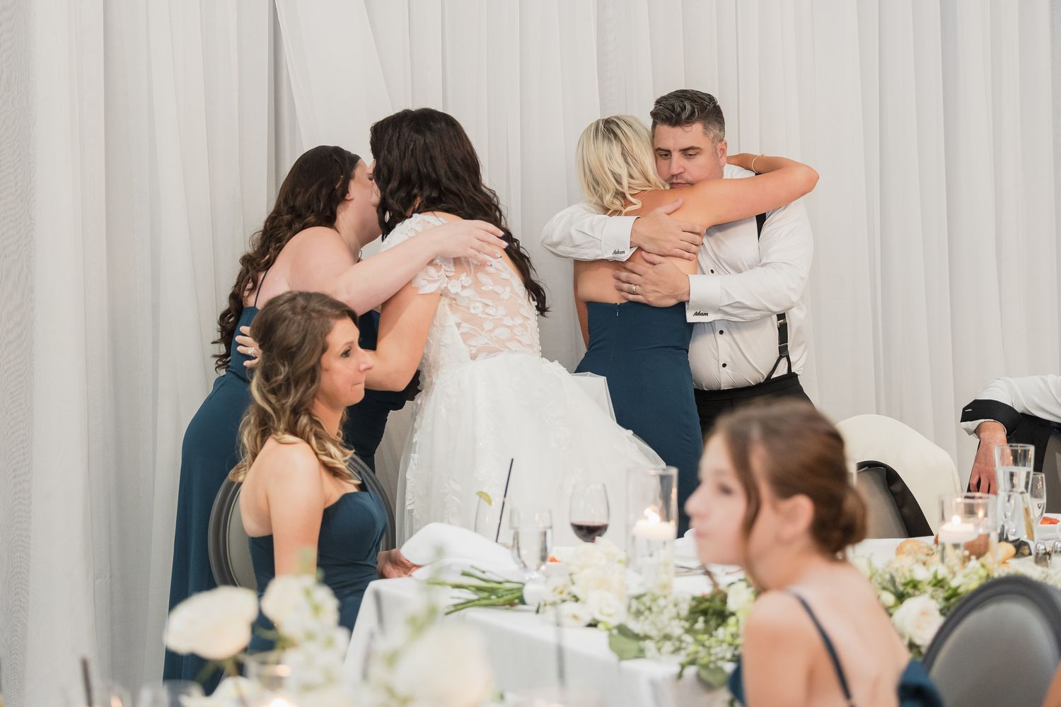 Bride and groom share warm embraces with guests during wedding reception celebration.