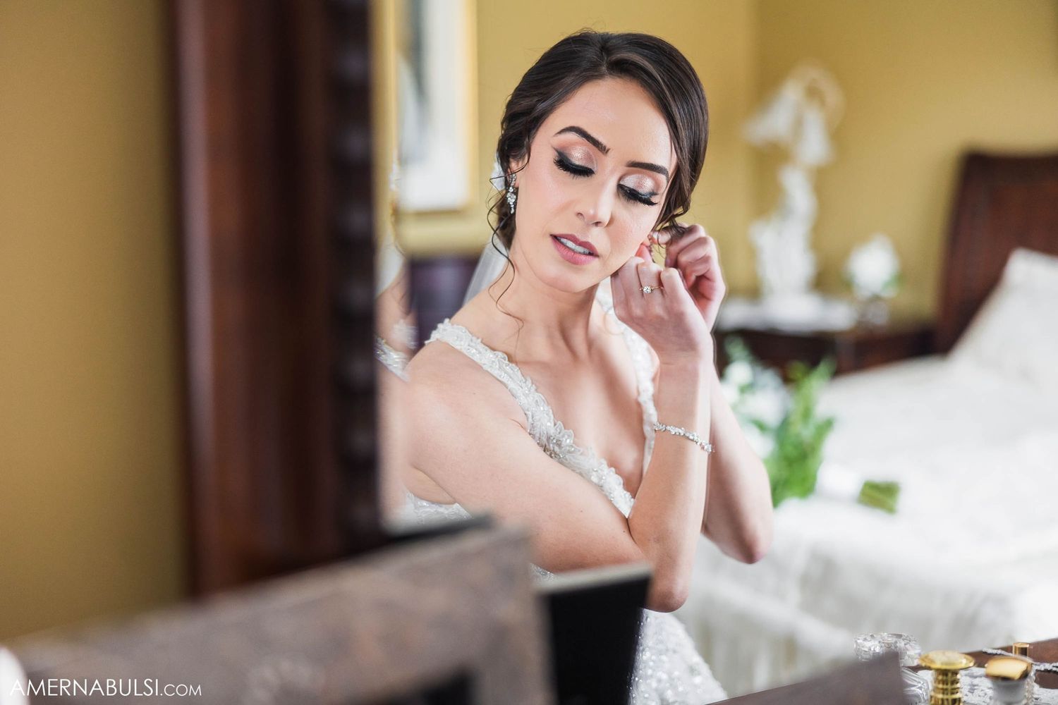 Close-up shot of someone putting on elegant earrings during wedding preparations.