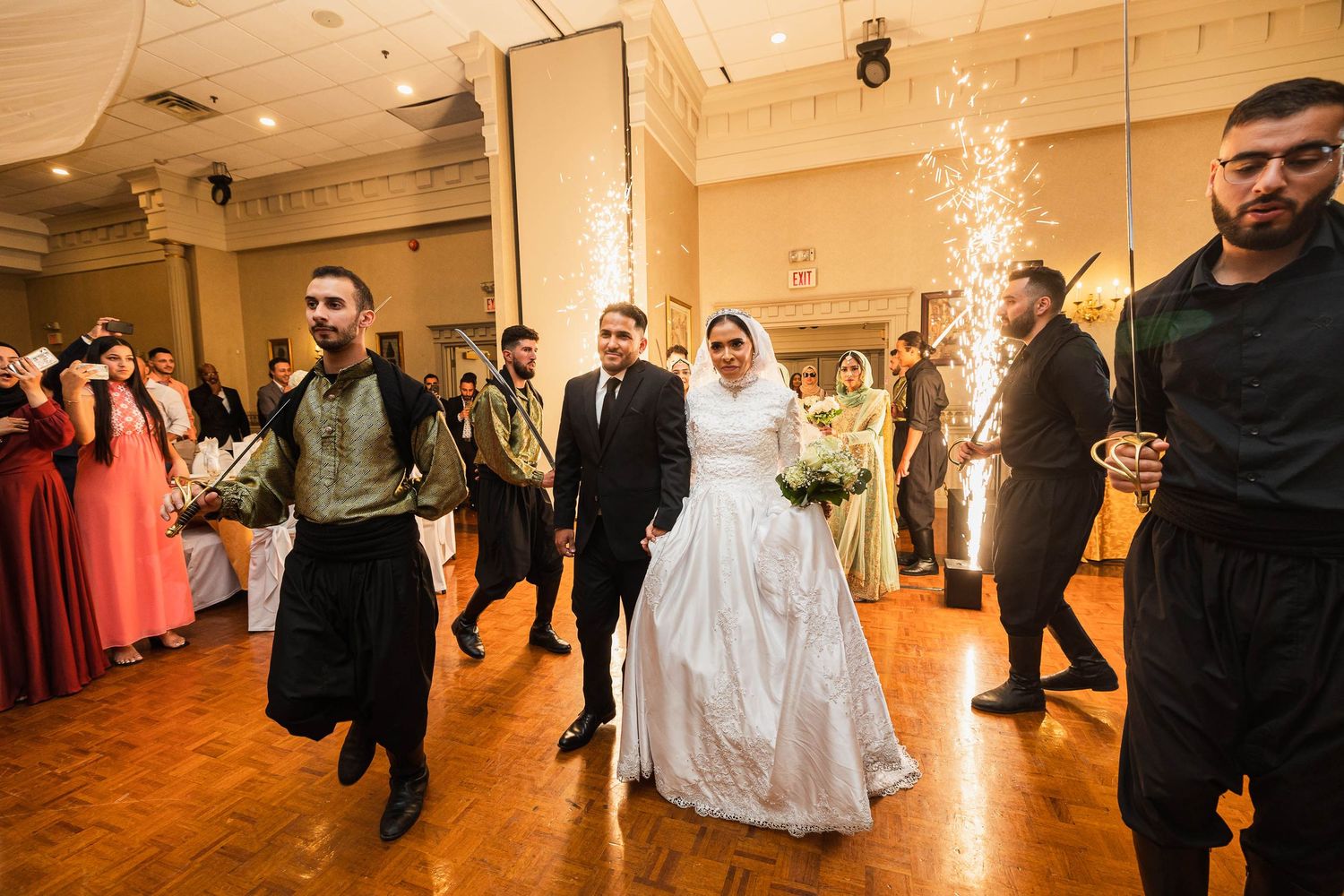 A wedding celebration in a ballroom with guests dancing and celebrating.
