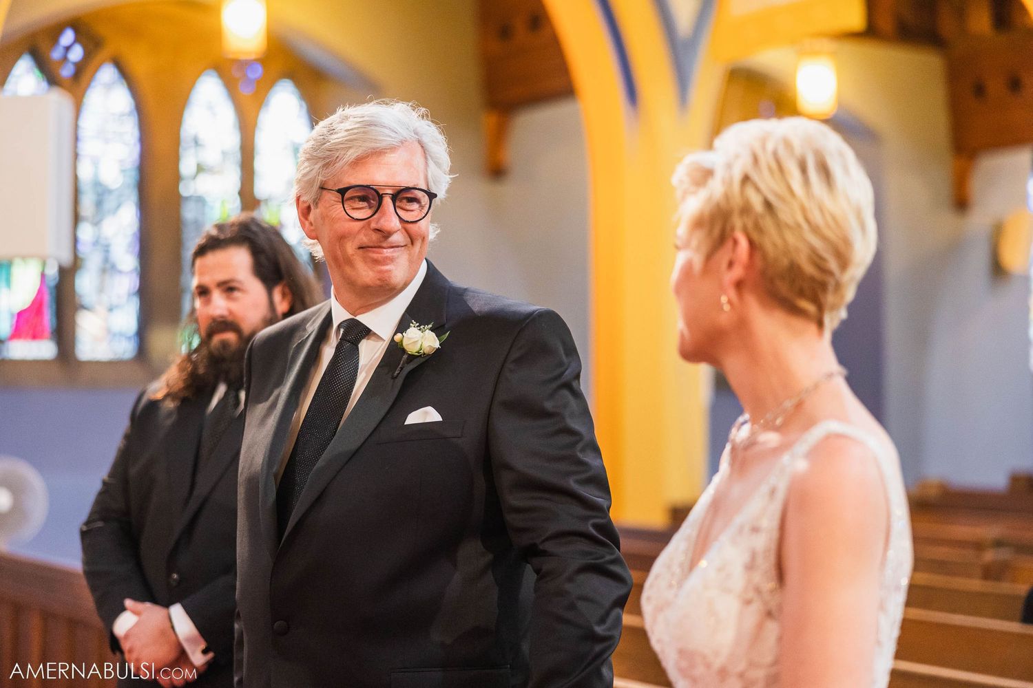 Wedding ceremony taking place under ornate church arches and stained glass.