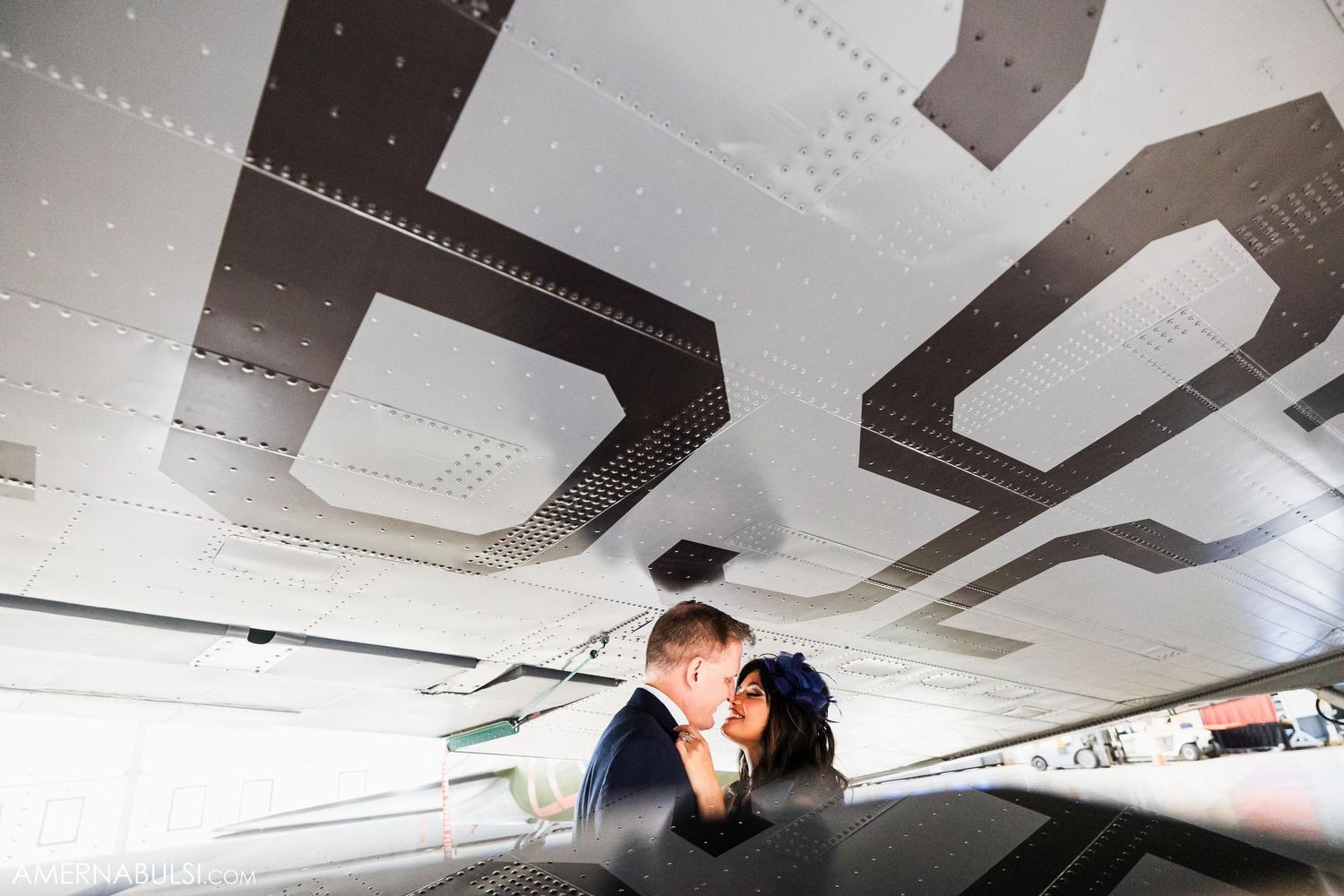 Intimate moment captured under airplane wing with industrial details.