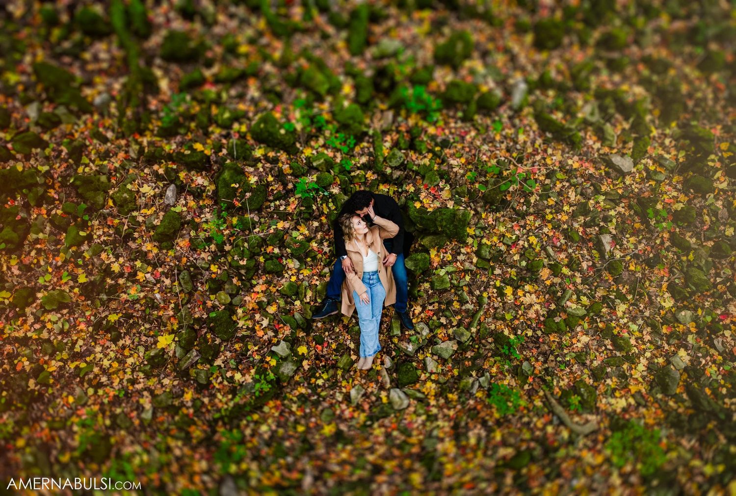 An aerial view of a couple standing among blooming spring flowers in a field.