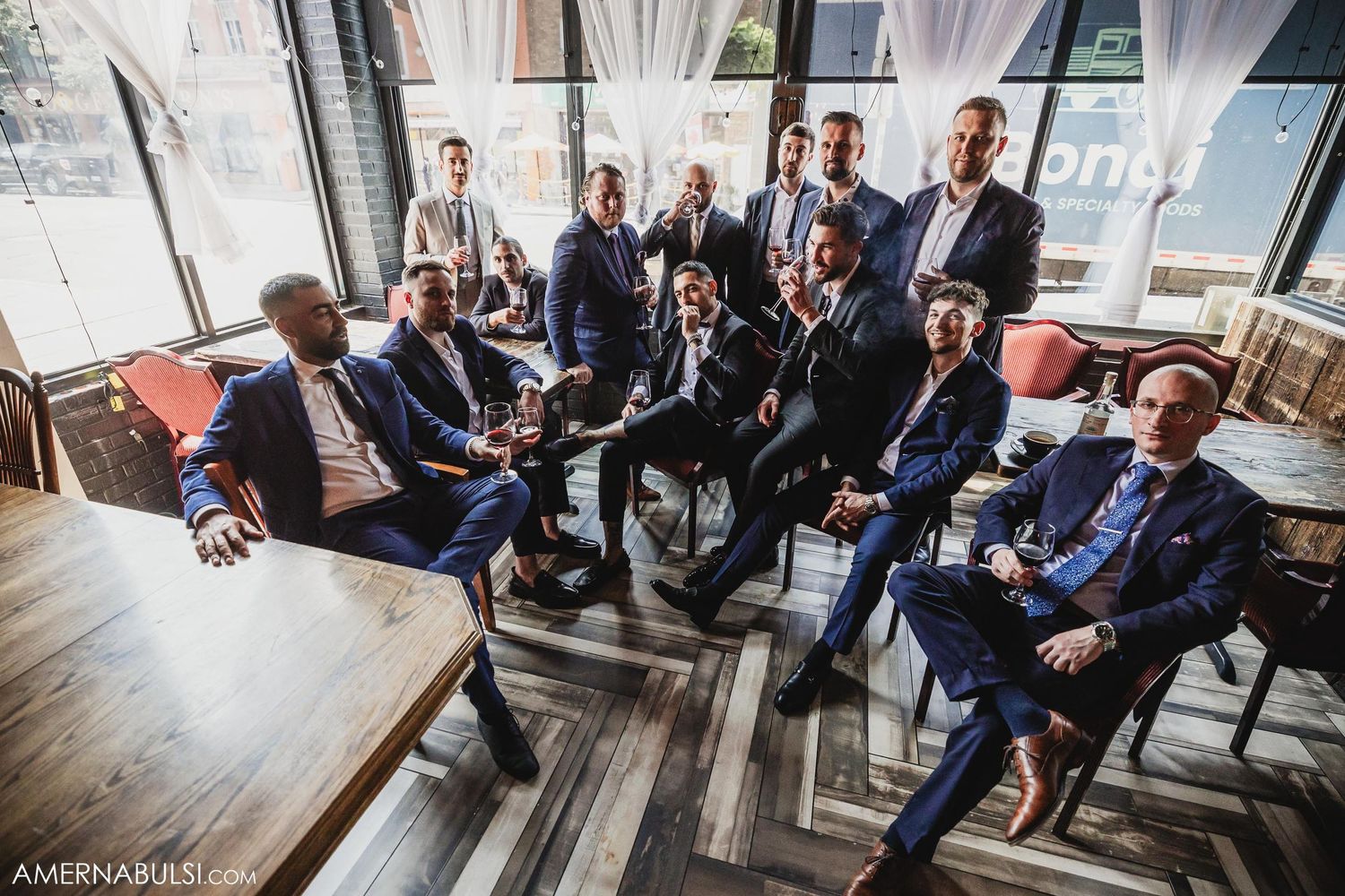 Group of men in suits gather casually in modern lounge setting.