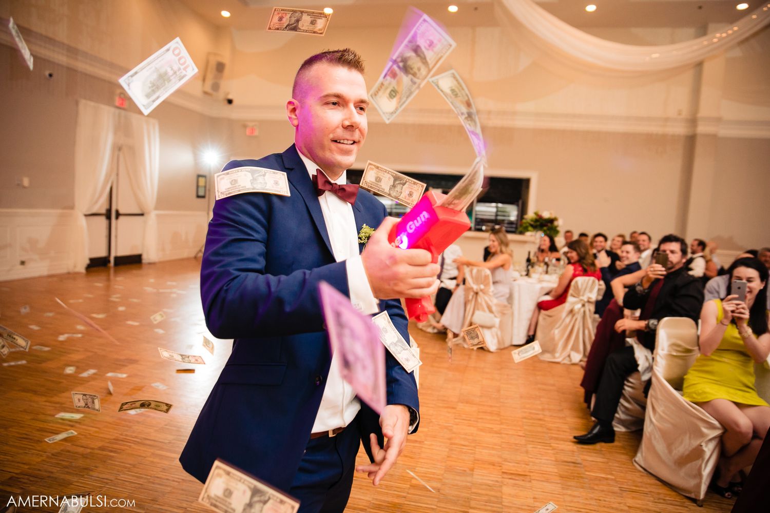 Wedding guests dance and celebrate on a warmly lit ballroom dance floor during an evening reception.