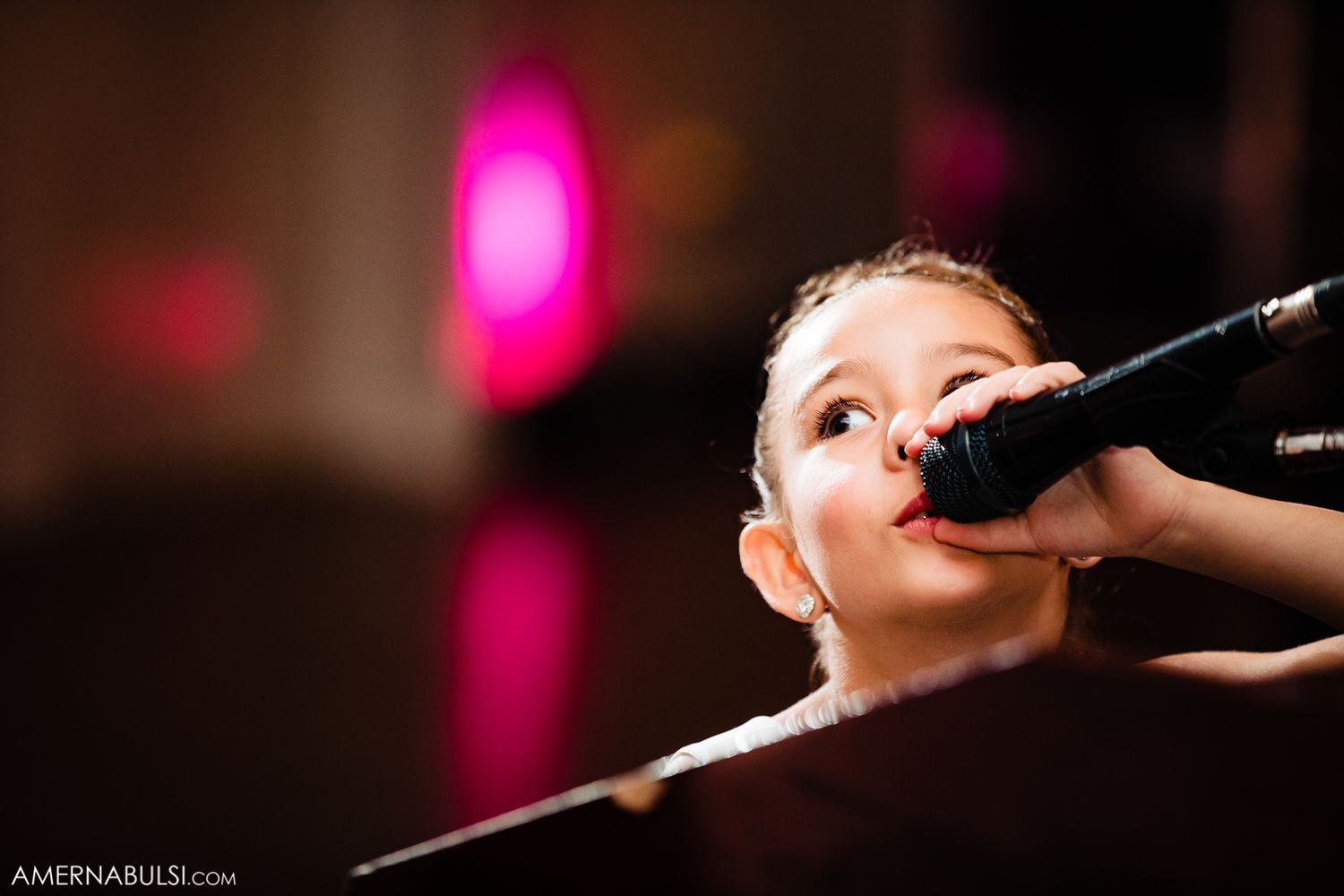 Pink stage lighting creates dramatic atmosphere during wedding reception entertainment.