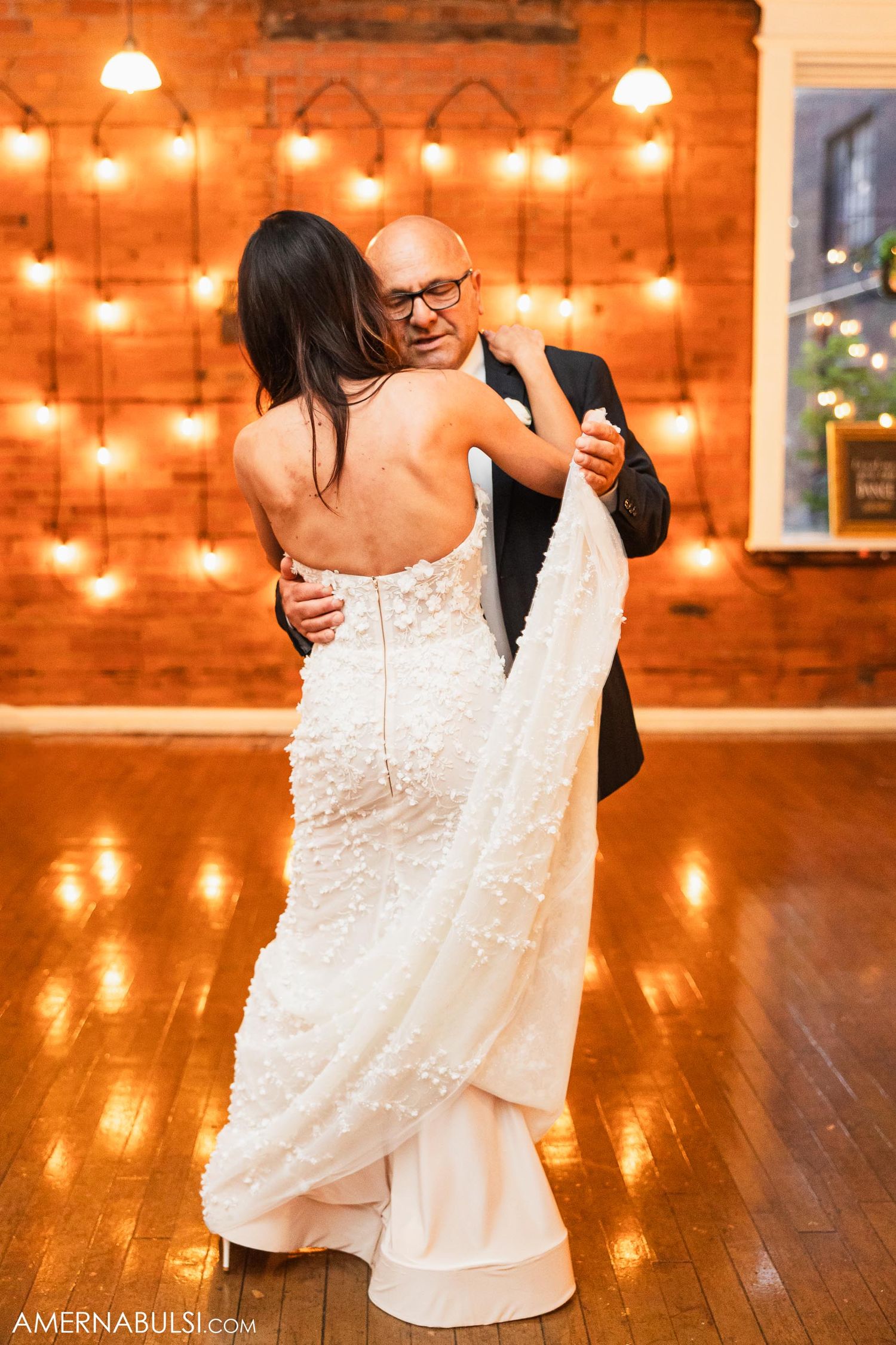 A romantic dance moment under warm string lights on a wooden floor.