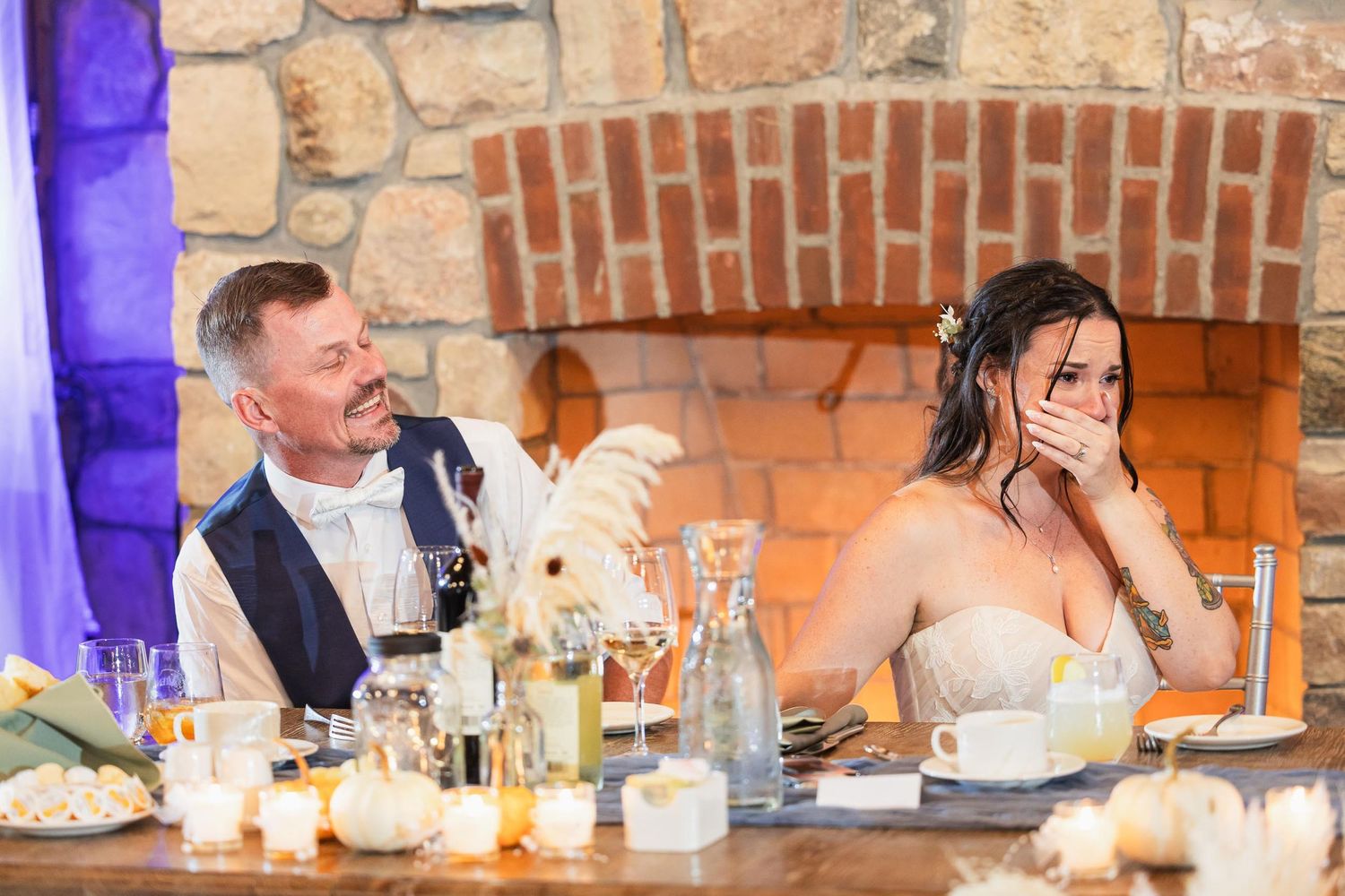 A candid reception moment captured at a rustic venue with stone walls and mood lighting.