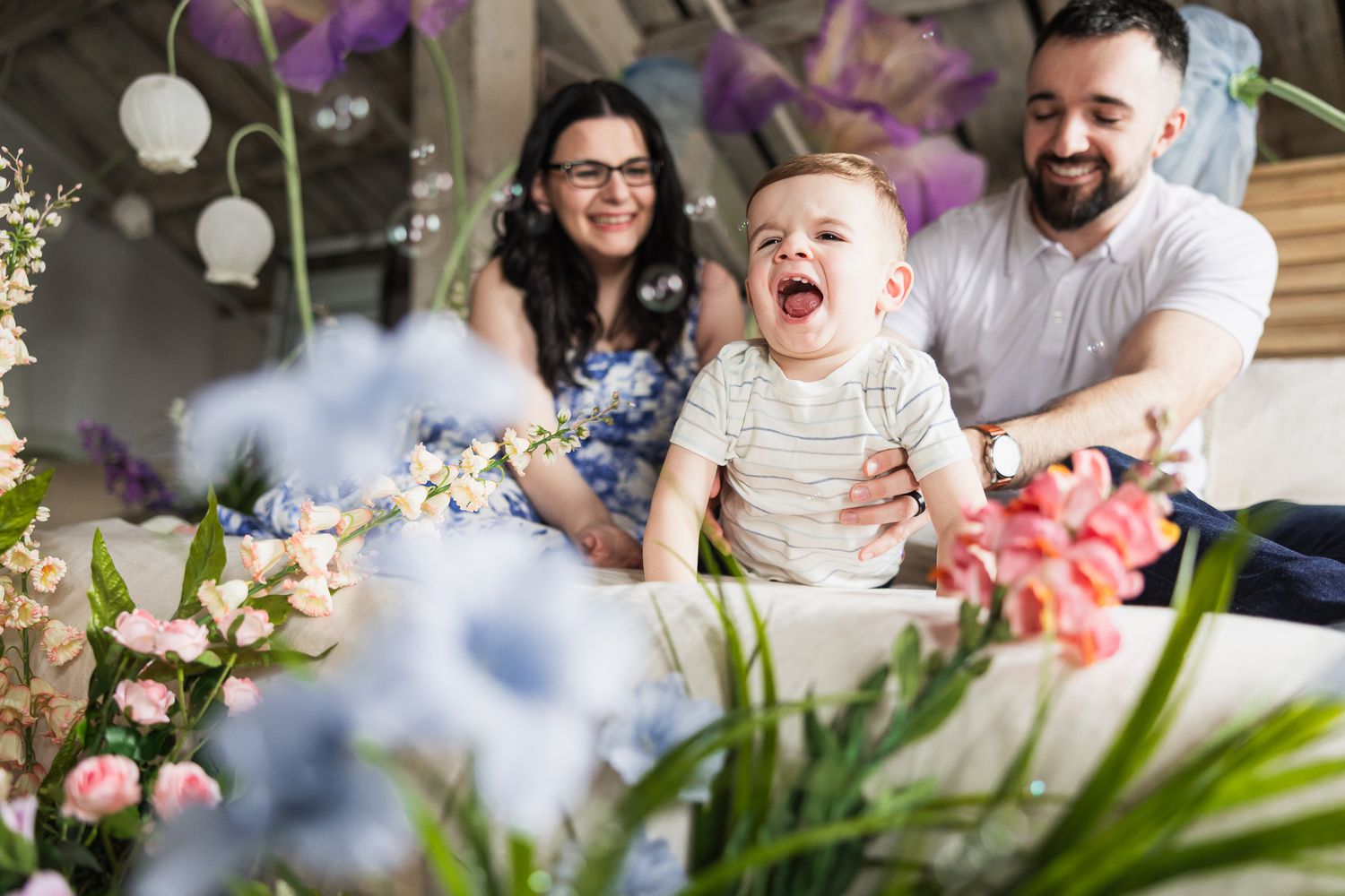 A candid family moment filled with laughter amid colorful spring flowers and decorations.