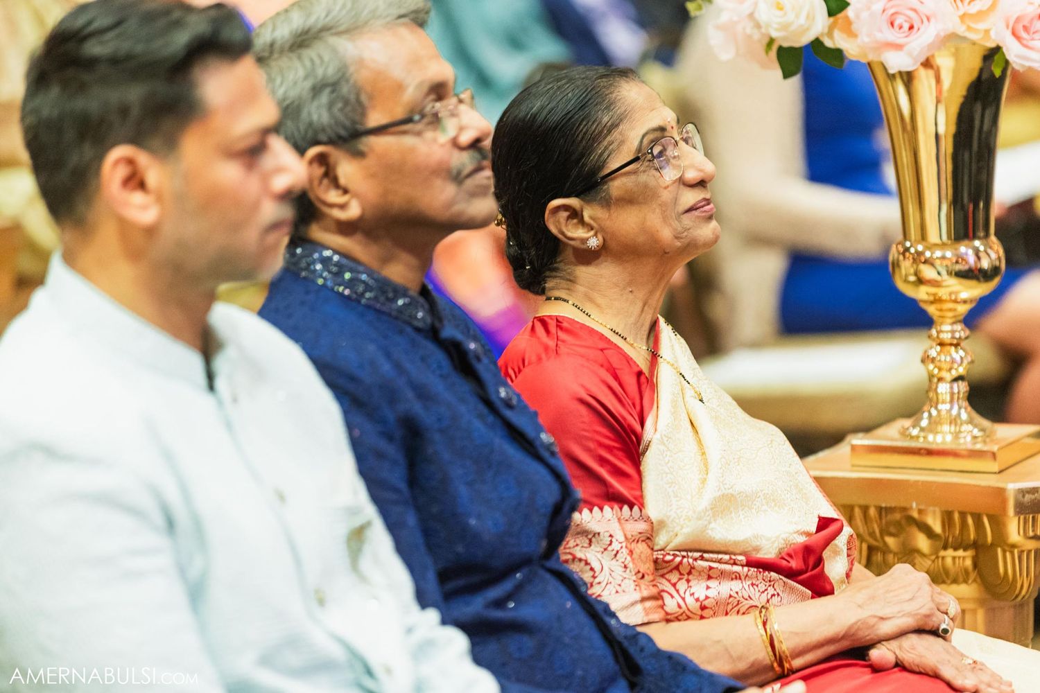 Wedding guests watching intently during a traditional Indian ceremony in an elegant setting.