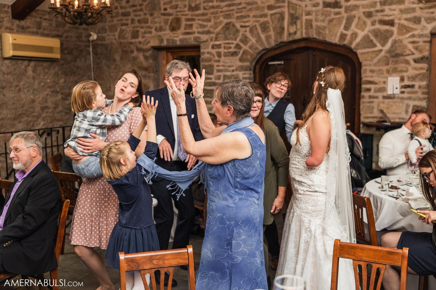 Lively wedding reception scene in stone-walled venue with guests celebrating.