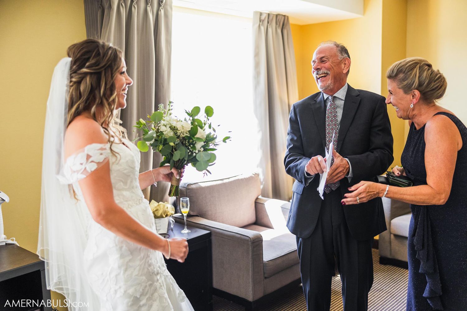 Wedding party members gather in a hotel room with sage green and yellow attire.
