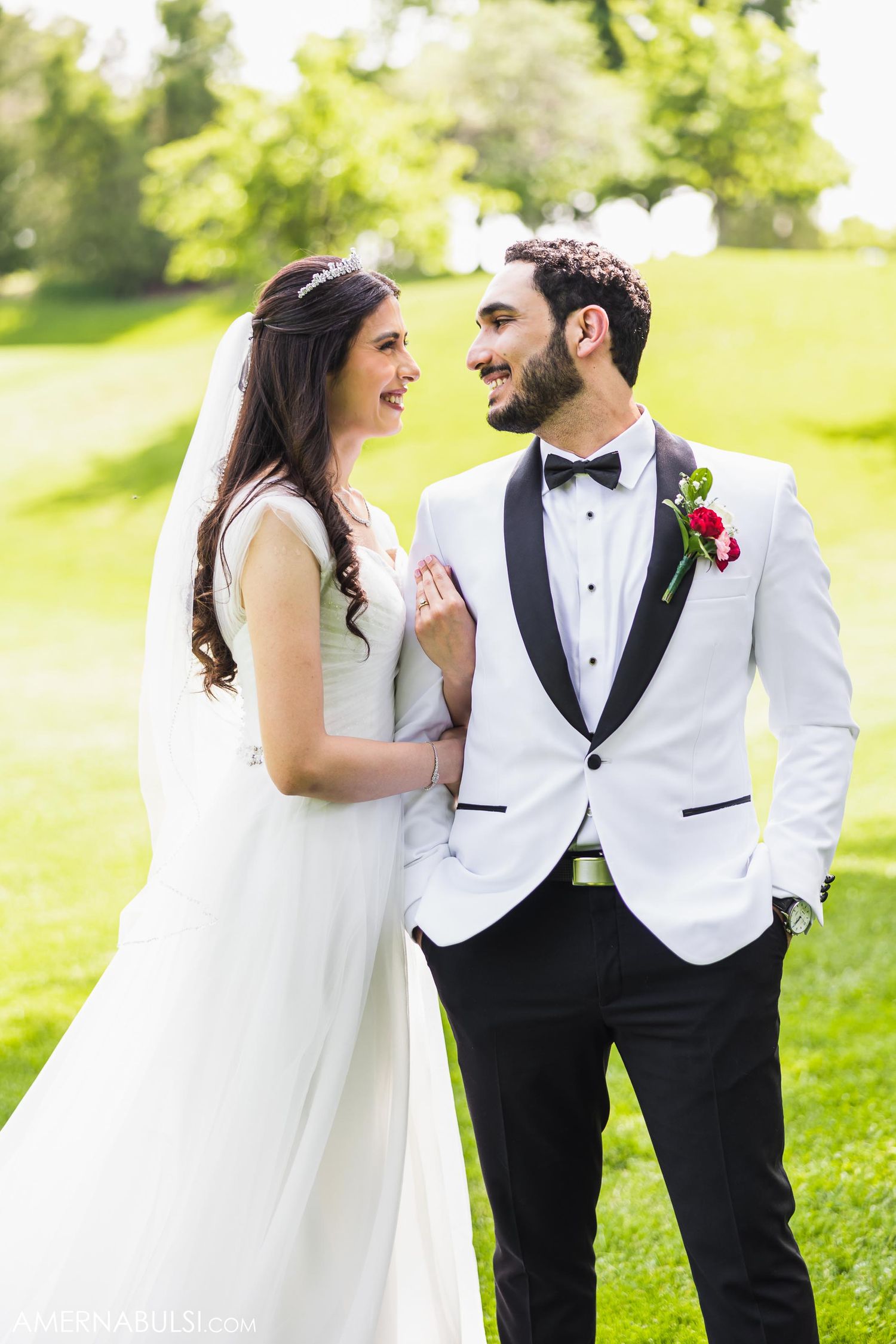 Bride and groom sharing a joyful moment together on their wedding day in a sunny garden setting.