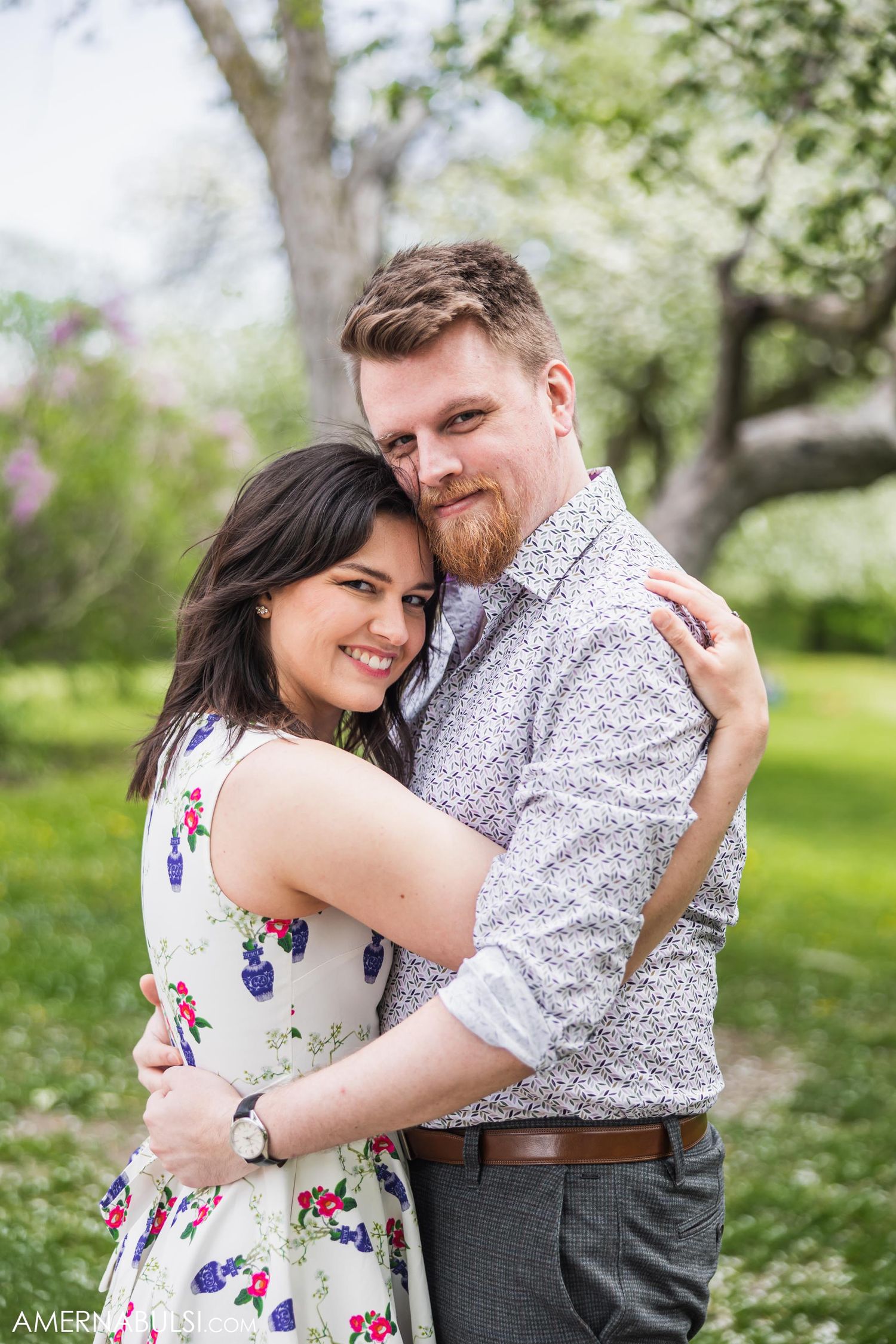 A tender embrace captured in a spring garden with flowering trees in the background.