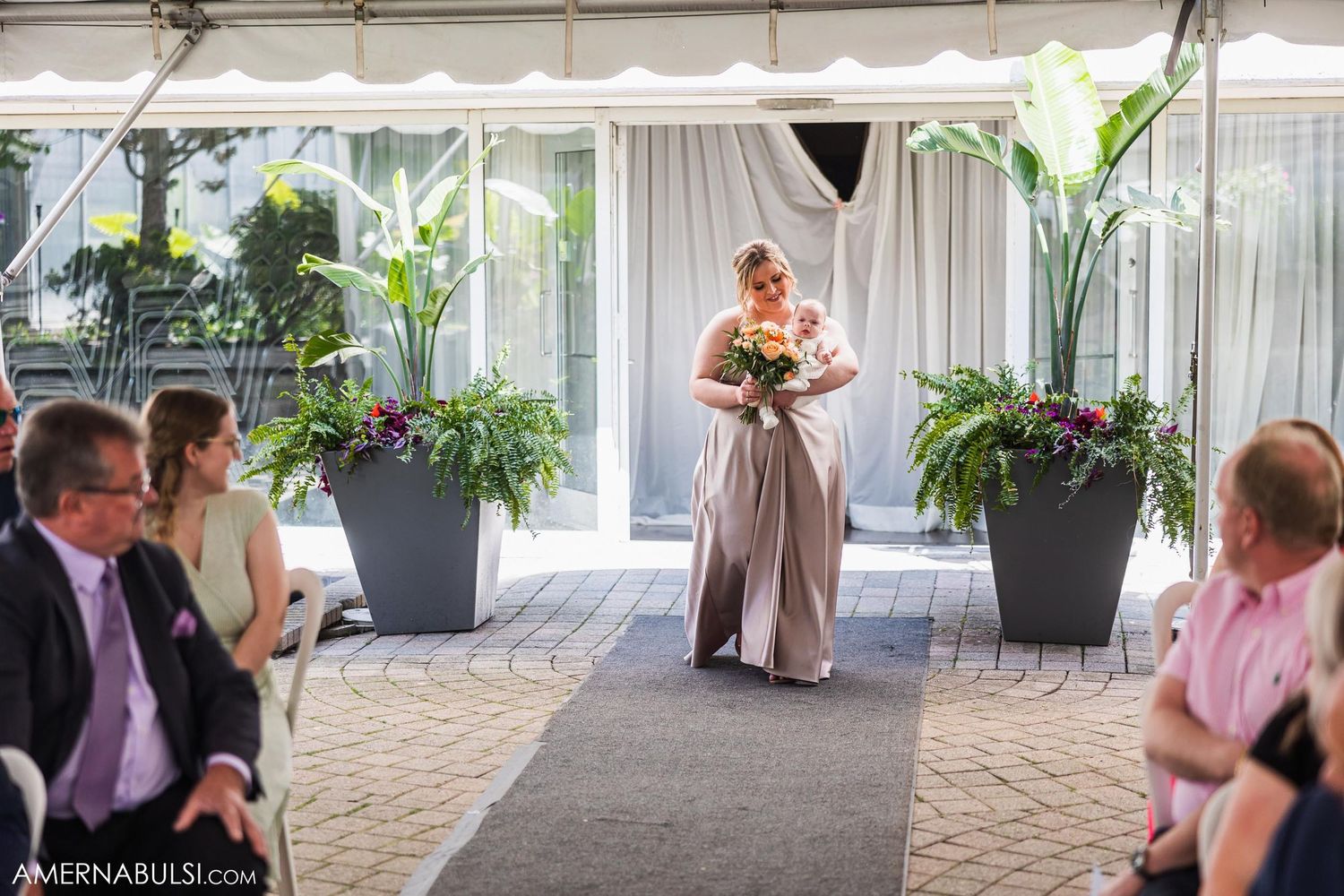 Wedding ceremony in a tented space with tropical plants and white draping.