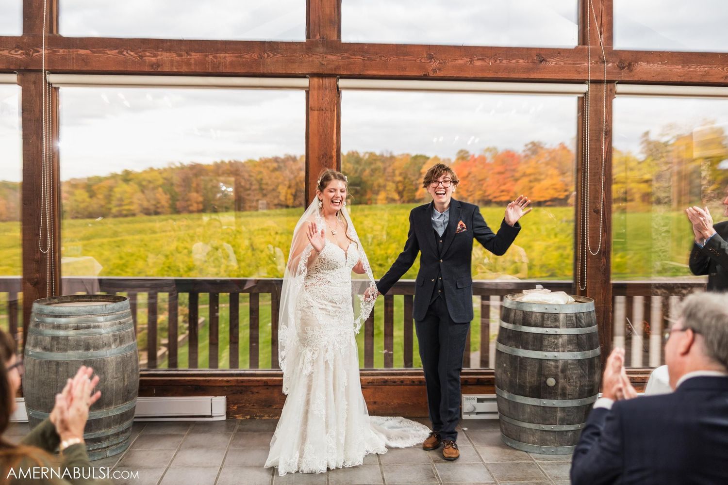 Newlyweds celebrate during ceremony in rustic venue with wooden beams and barrel decor.
