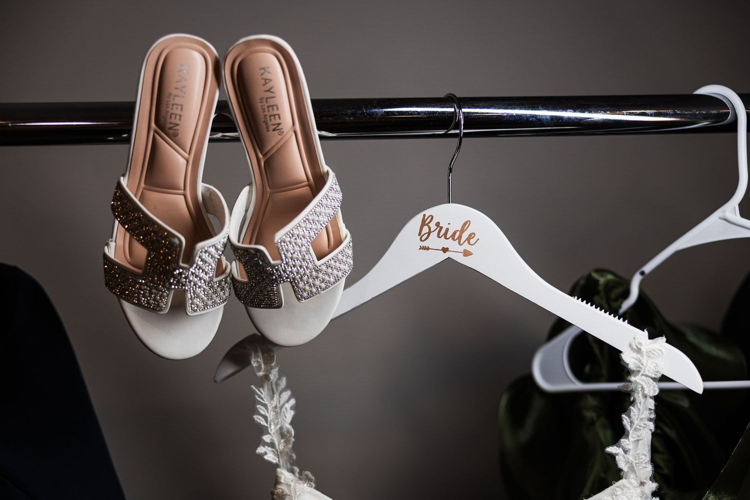 Bridal heels and white Bride hanger displayed on a clothing rack for a wedding day preparation.