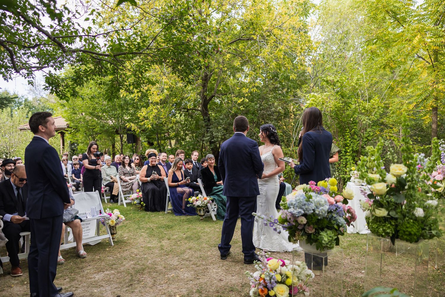 Outdoor wedding ceremony in a lush garden with guests seated as couple stands at the altar.