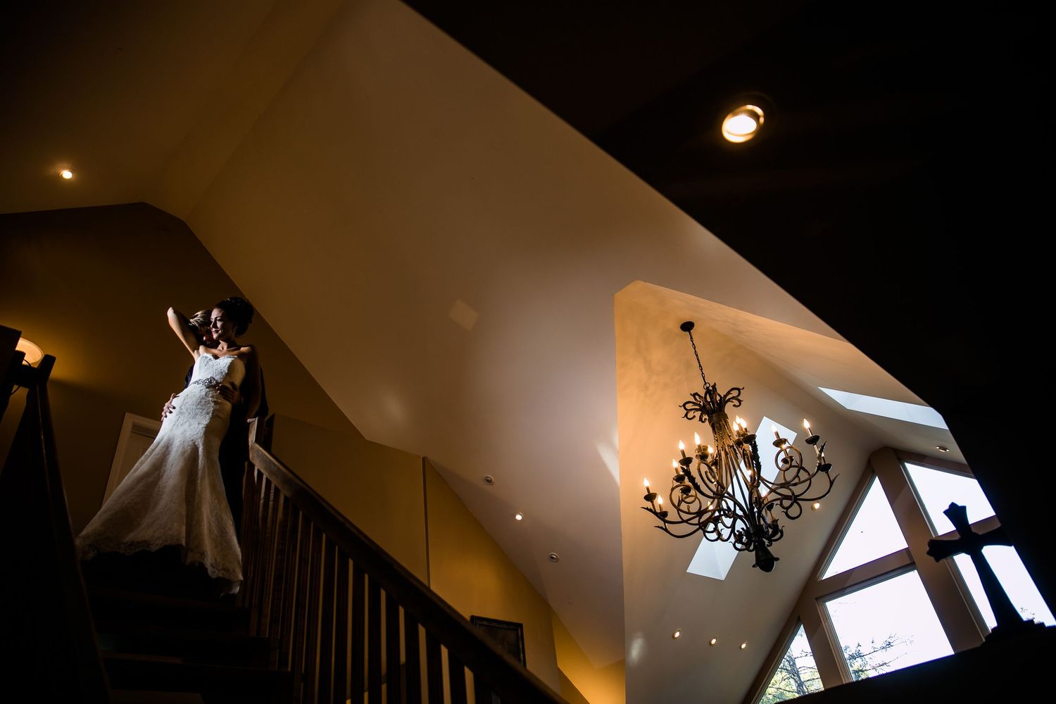 Artistic silhouette shots of a wedding dress hanging in venue with dramatic lighting.