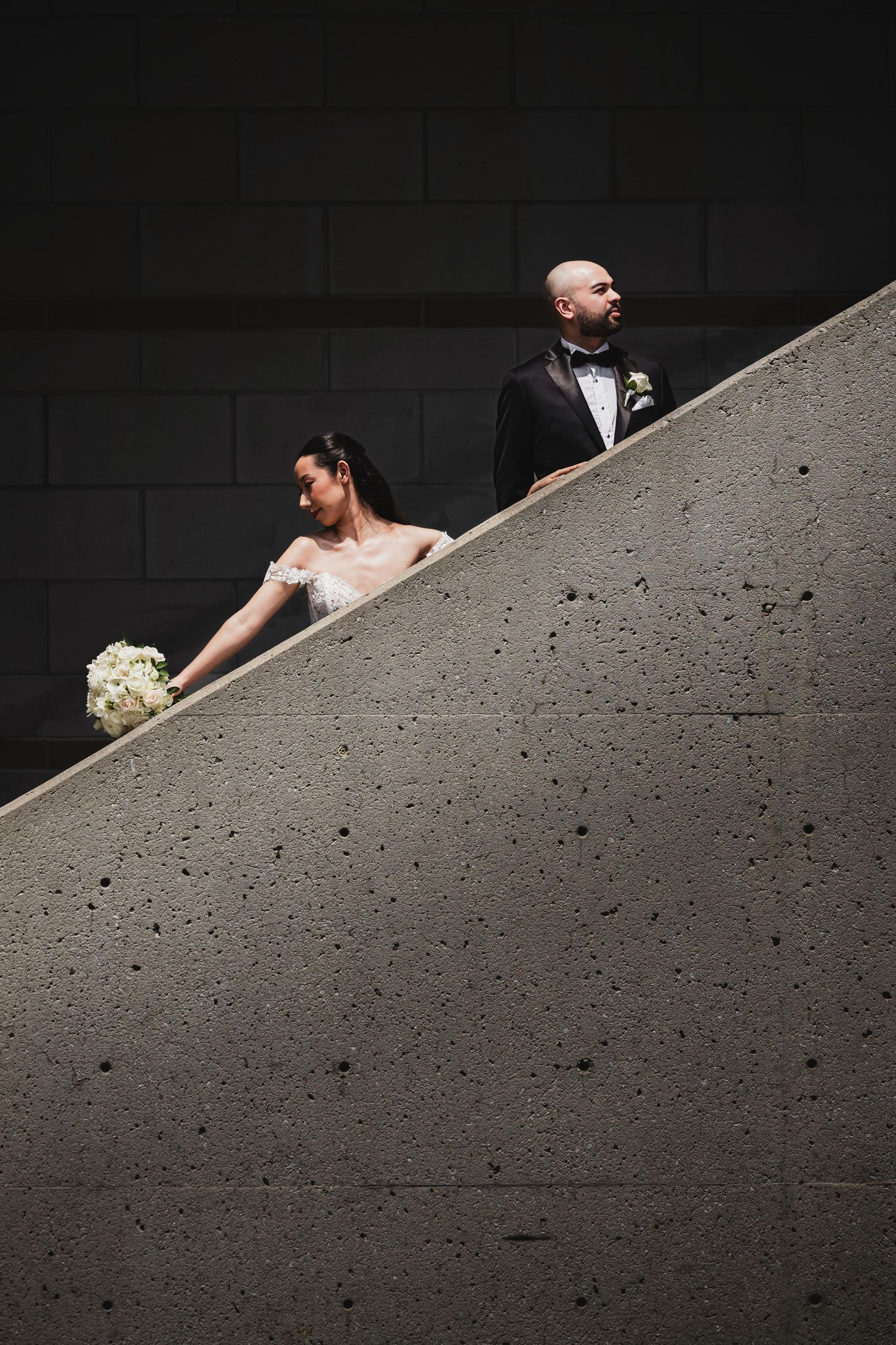 Artistic wedding photo composition using diagonal concrete architecture and shadows.