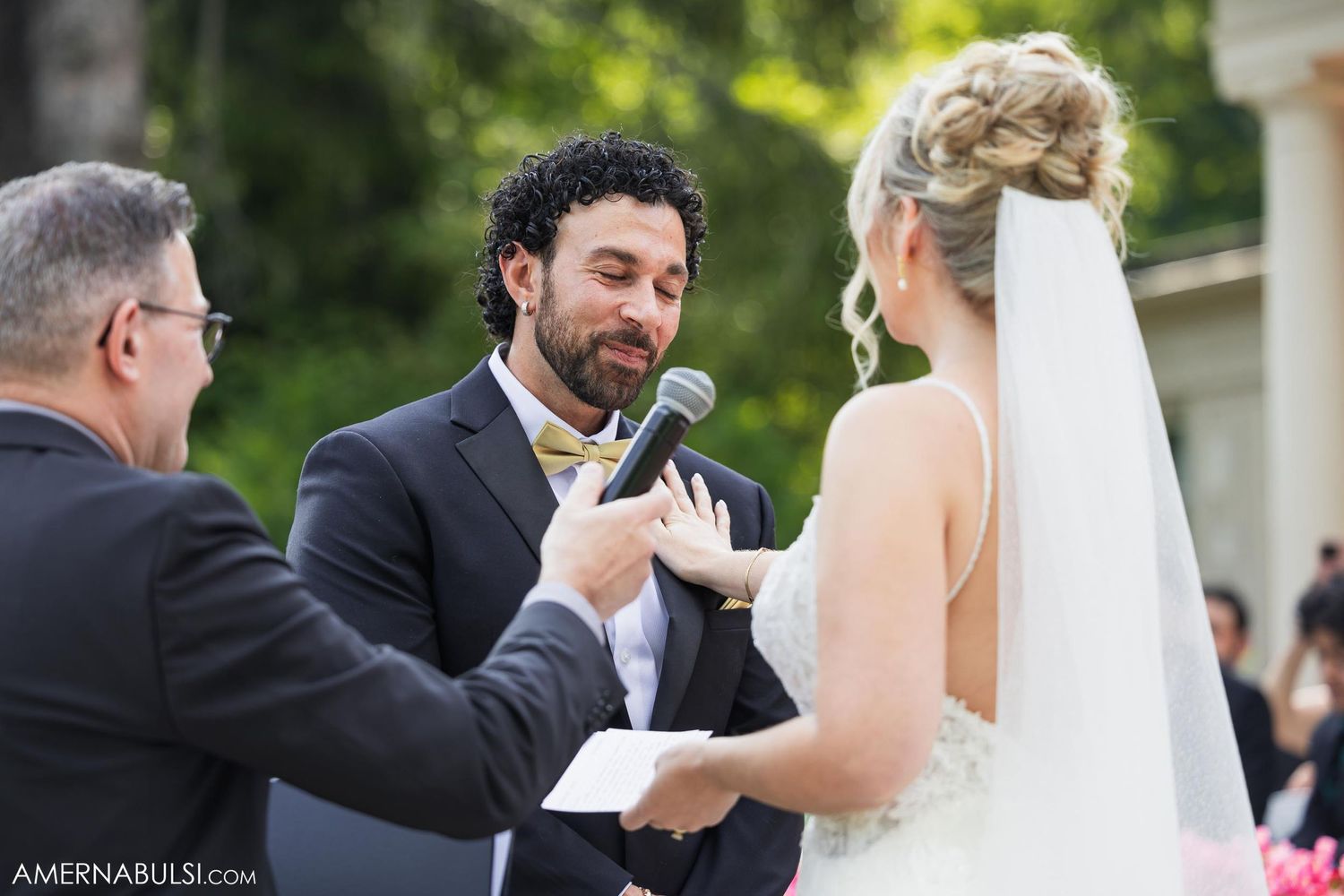 Wedding ceremony showing couple exchanging vows with microphone held by officiant.