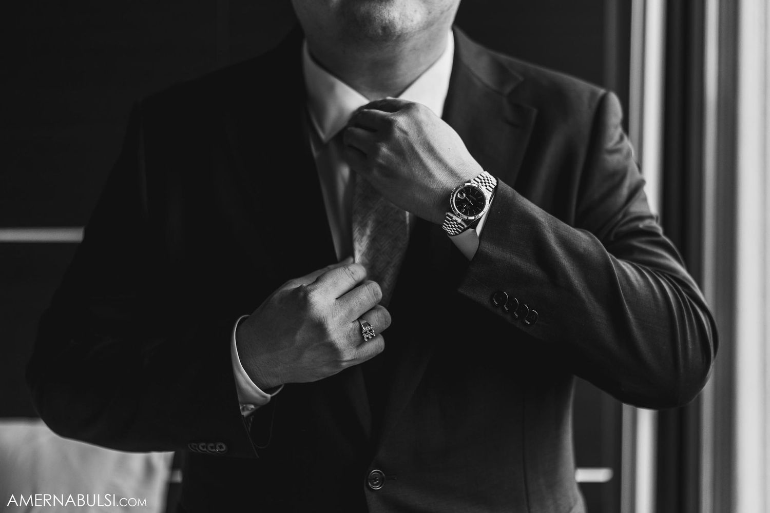 Black and white photo of formal suit adjustment with watch detail.
