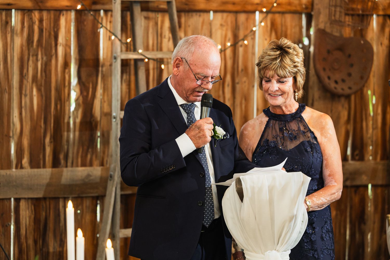 Emotional moment during wedding reception in rustic wooden barn with romantic lighting.