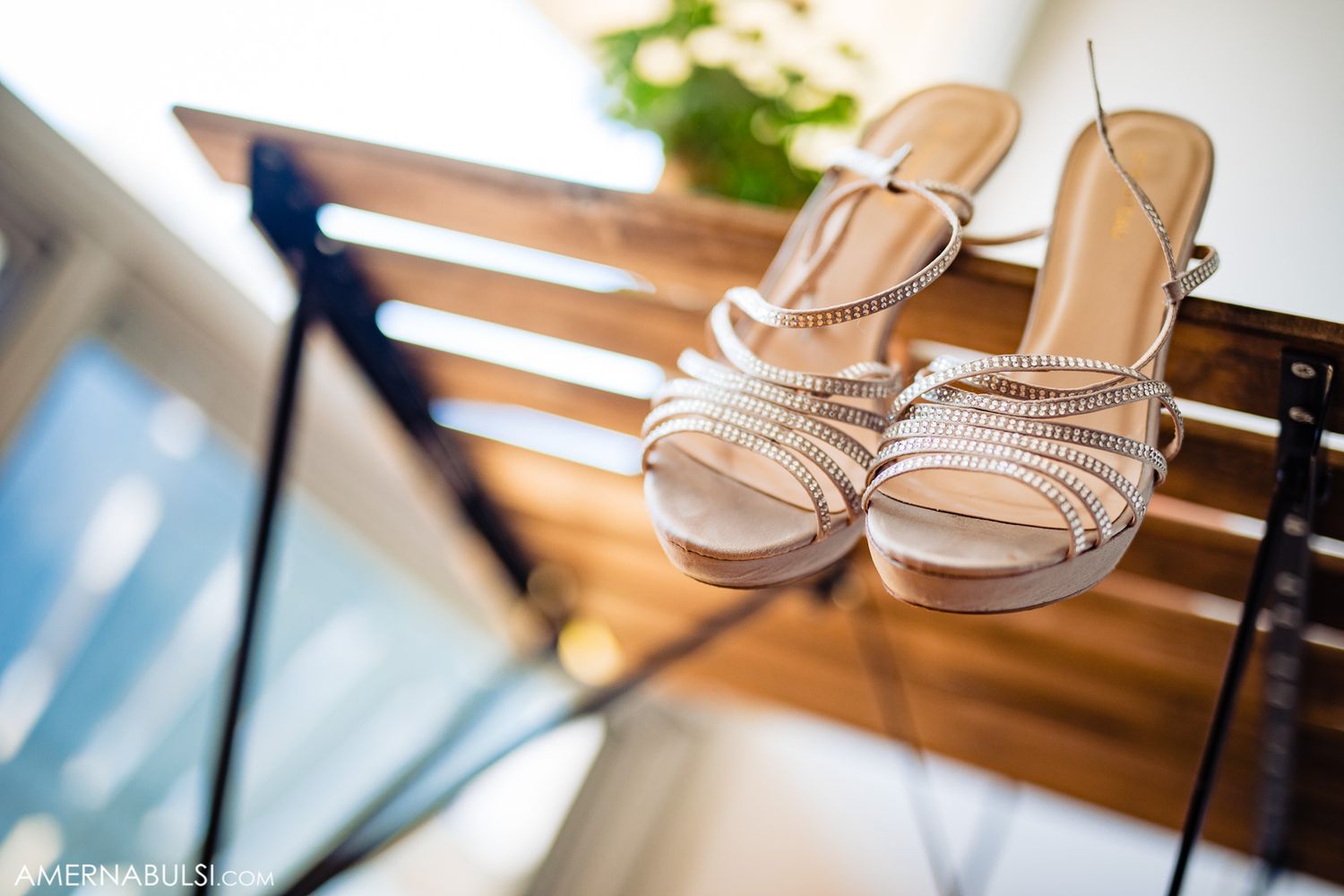 Elegant strappy wedding sandals displayed on wooden surface with blurred background.