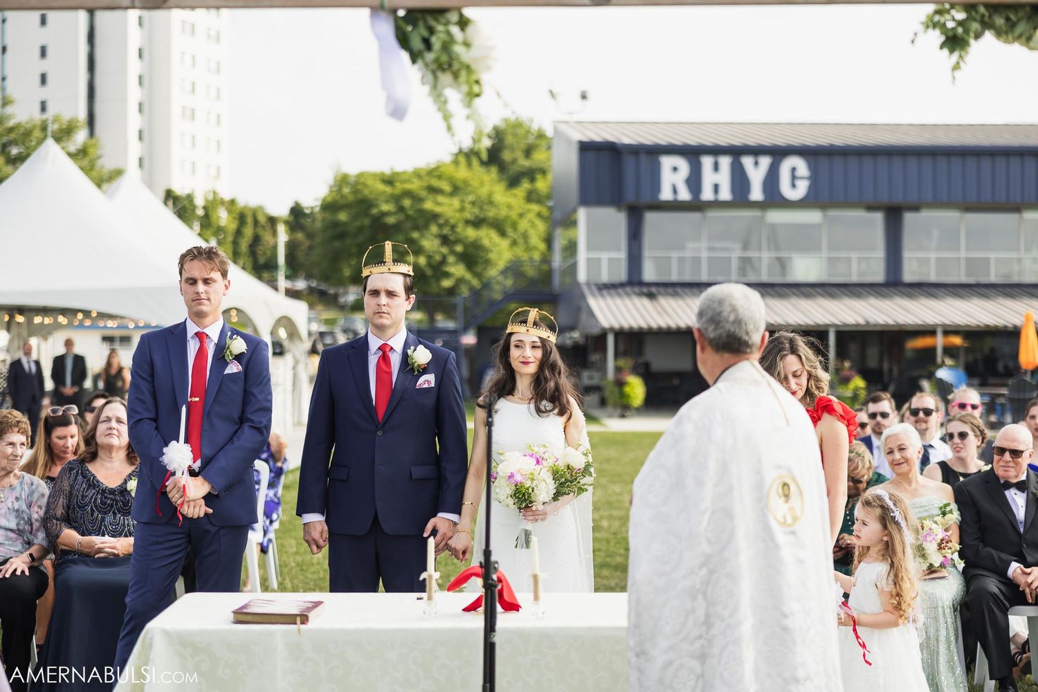 Outdoor wedding ceremony taking place in front of RHYC building with white altar setup.