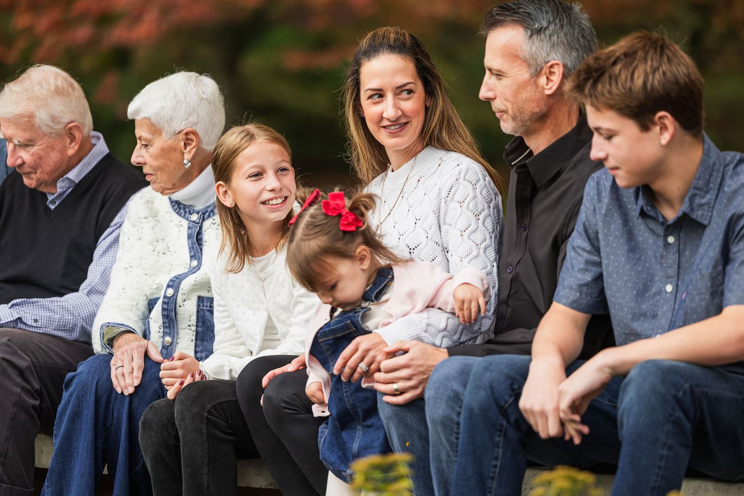 Extended family sits together on wooden steps for a casual outdoor portrait session.