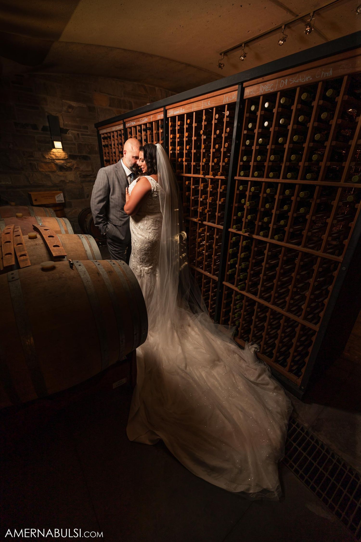 Romantic moment in wine cellar with dramatic lighting and wine rack backdrop.