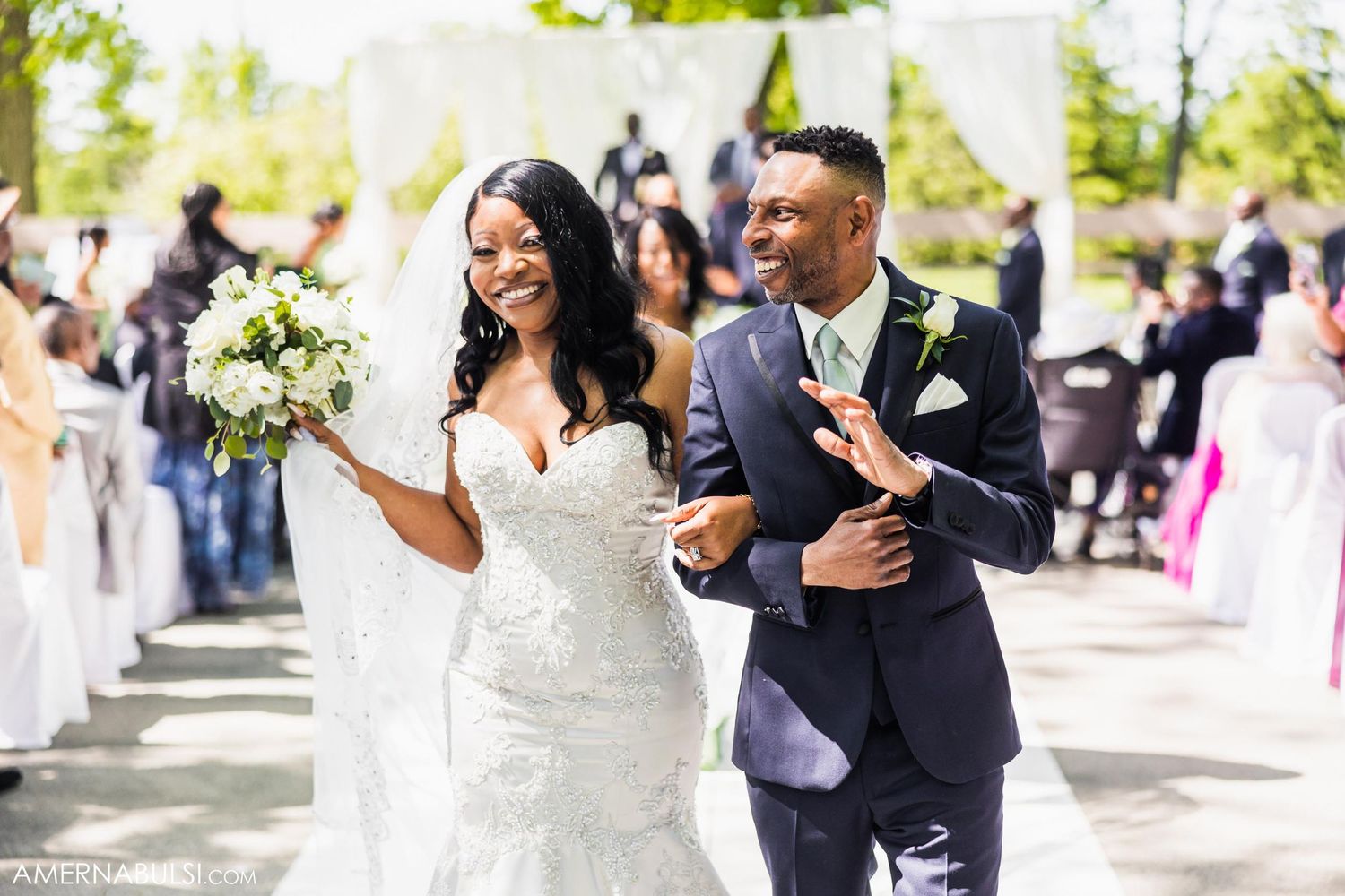 Newlyweds share joyful moment walking down aisle after outdoor wedding ceremony.