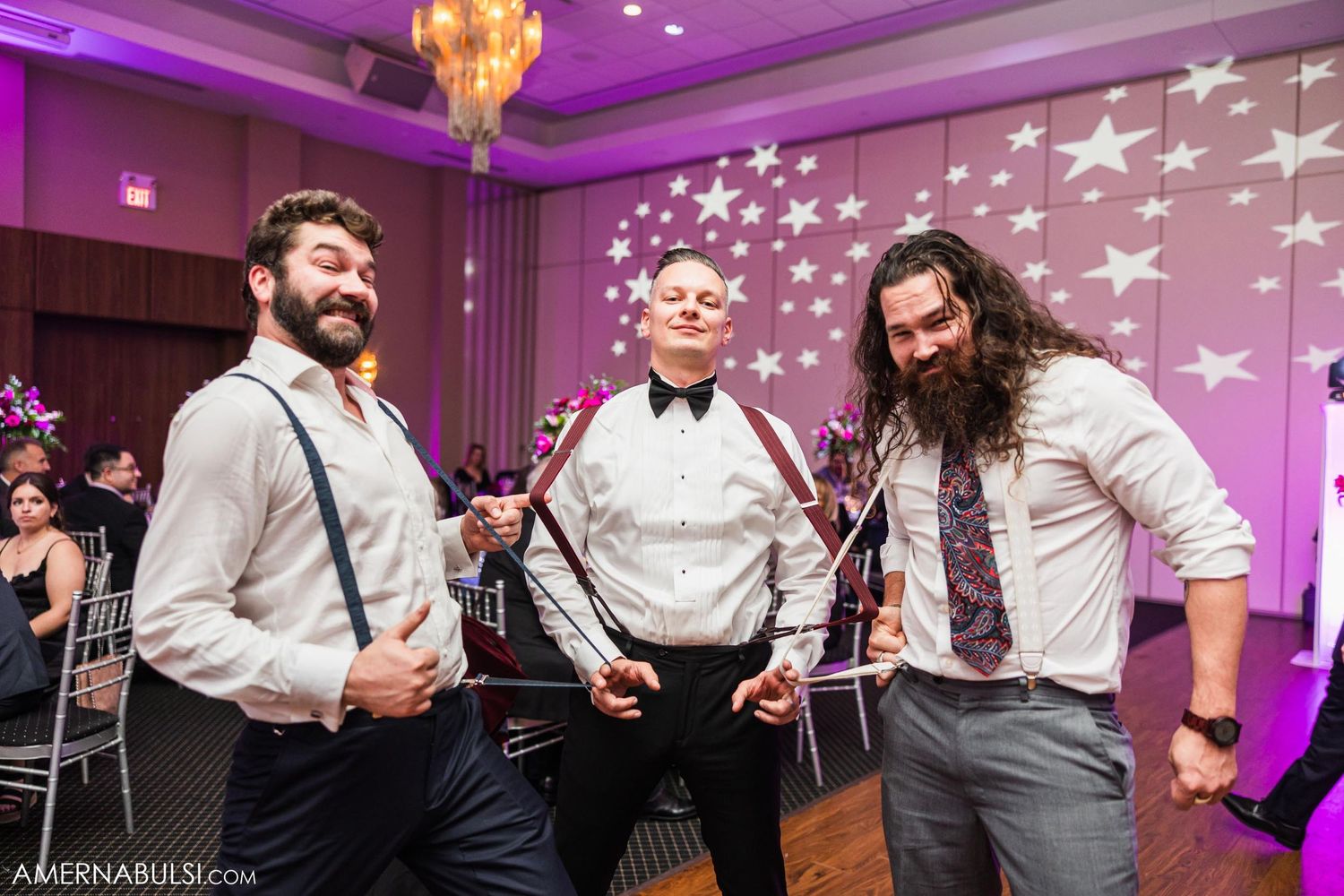 Three guests having fun at wedding reception with pink and white star decorations.