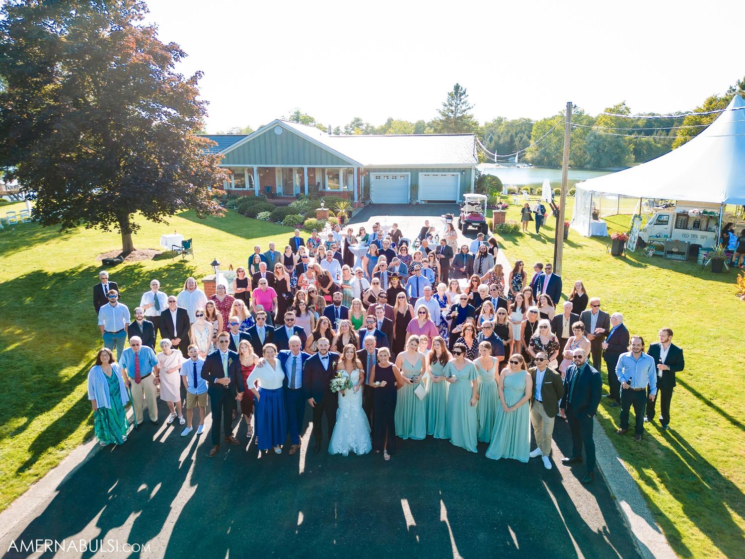 Aerial view of large wedding party and guests gathered outside venue.