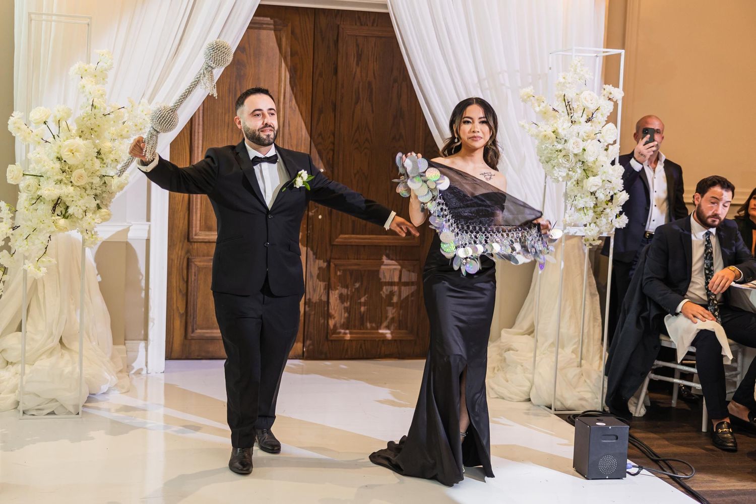 Grand entrance in an elegantly decorated venue with white drapes and floral arrangements.