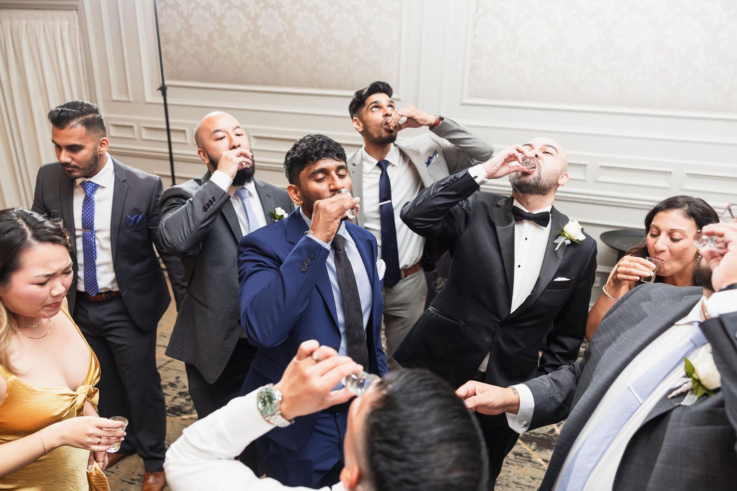 Wedding party guests taking shots together at reception celebration.