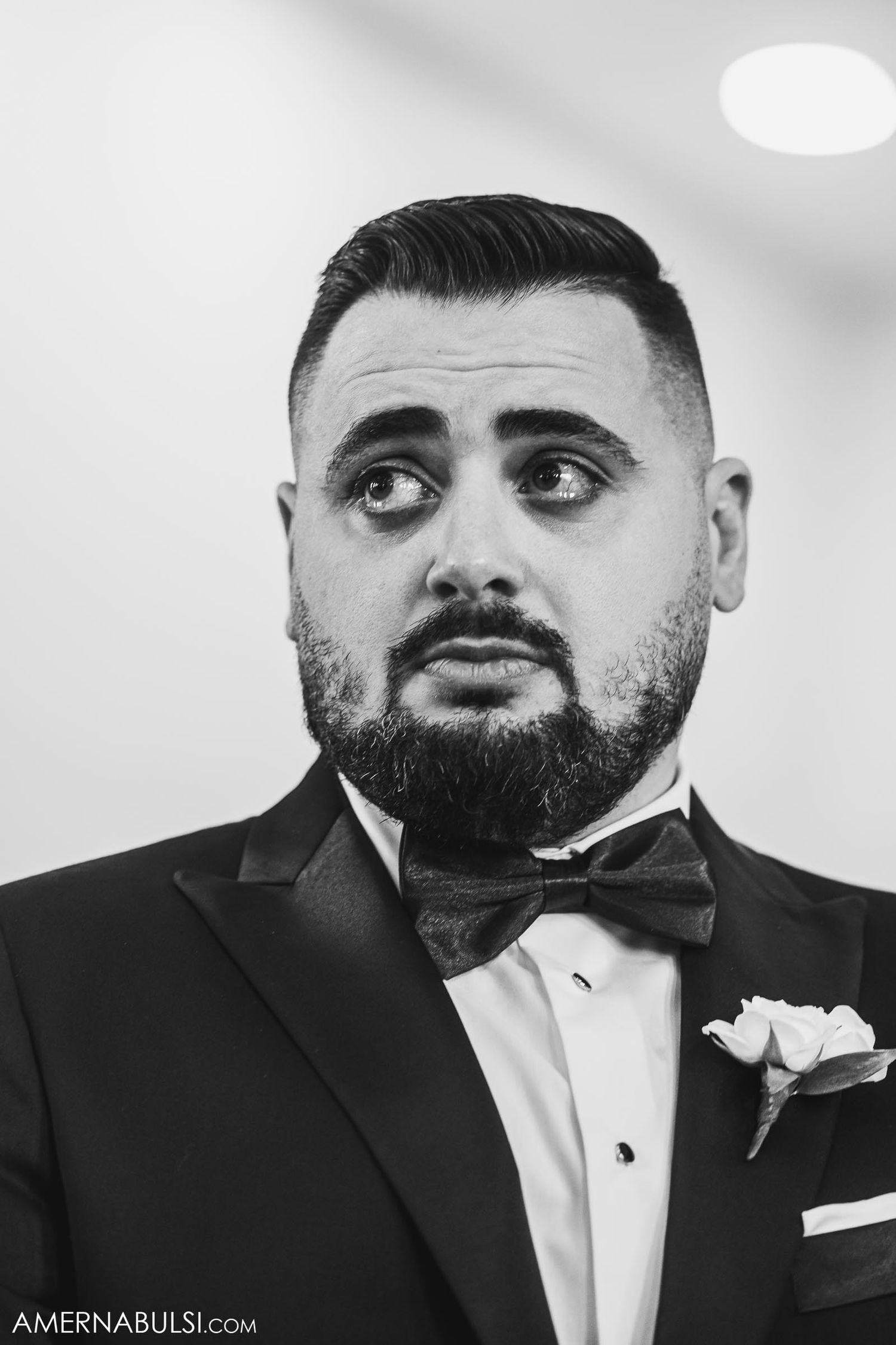 Black and white portrait of groom in tuxedo and bowtie.