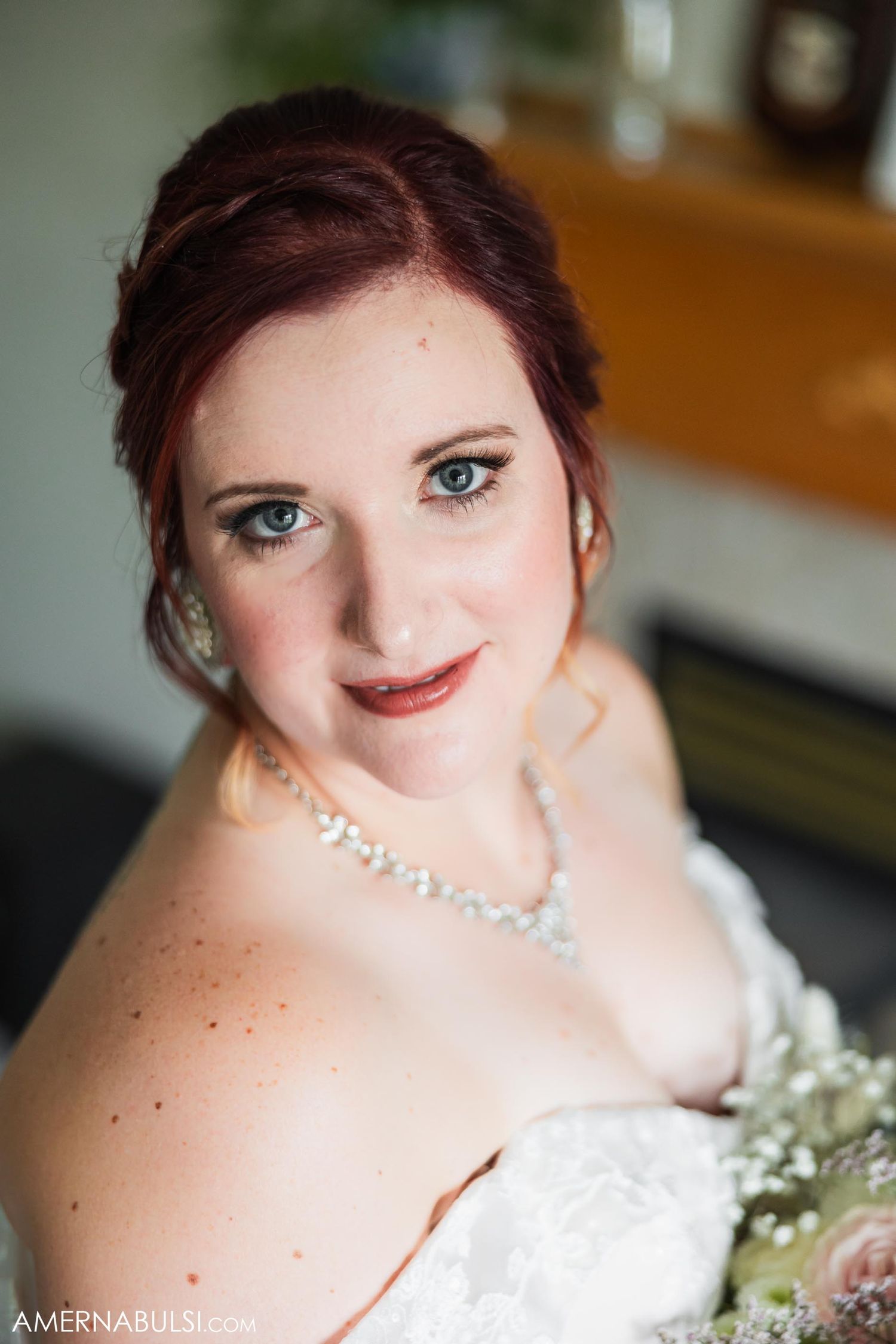 A bridal portrait showing elegant makeup, pearl necklace and white wedding gown.