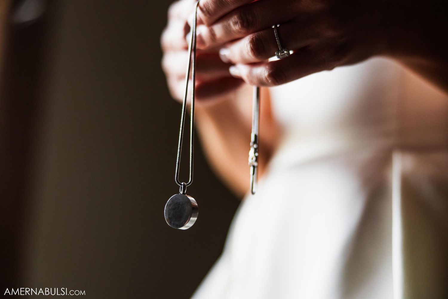 Close-up shot of hands holding crystal jewelry against white fabric.