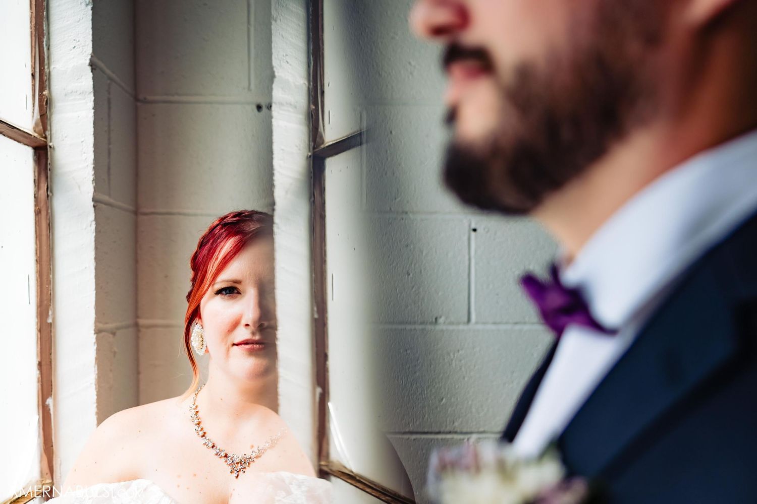 Close-up wedding portrait by window in industrial space.