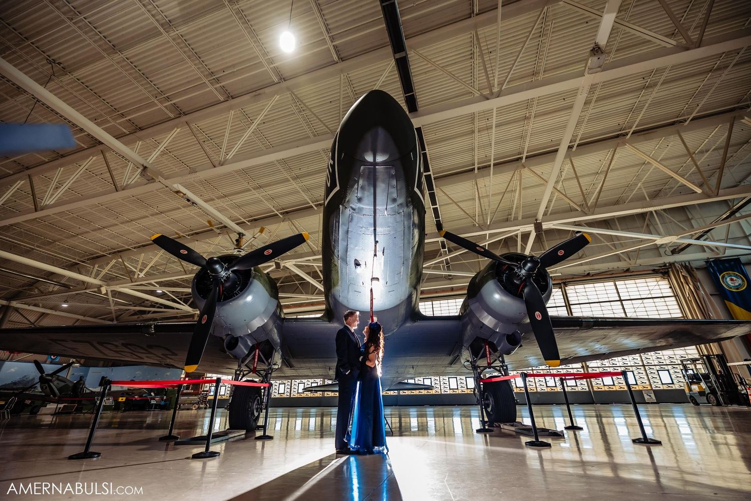 Vintage military aircraft with twin propellers displayed in an aviation museum under dramatic lighting.